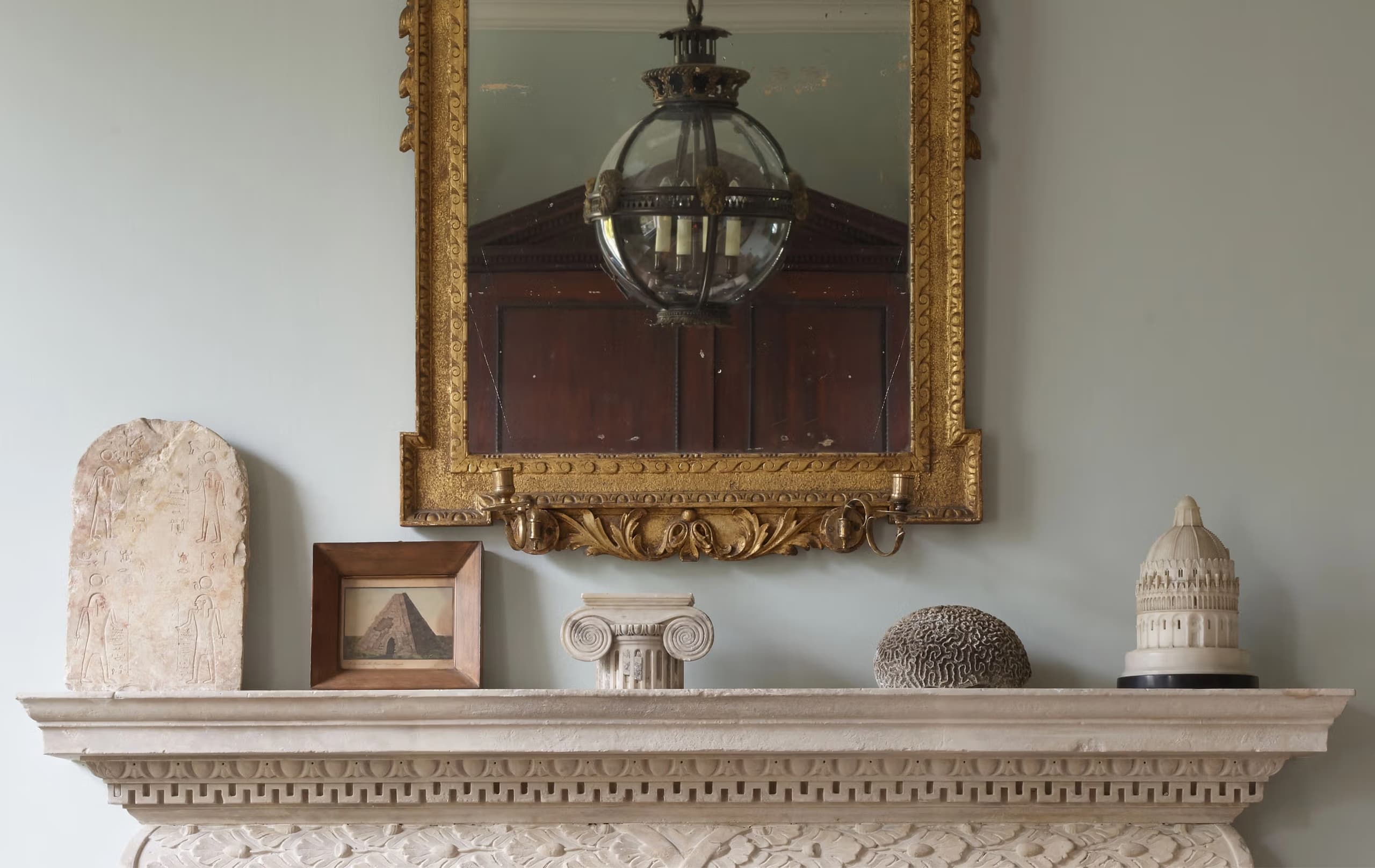 Jamb mantelpiece with gilded mirror, hanging lantern, and antiques